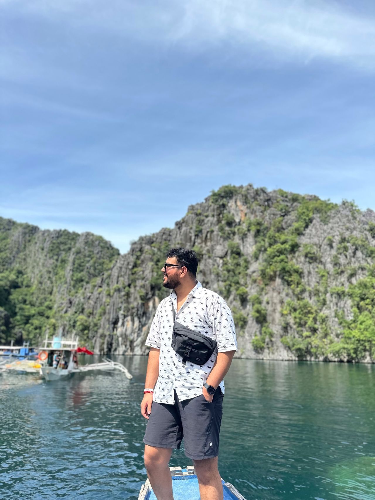 Standing at the front of a boat gliding past limestone cliffs and turquoise water in the Philippines