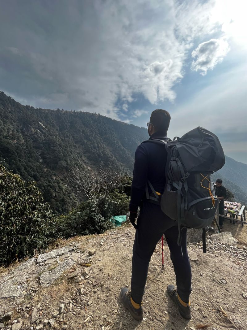 Standing on a mountain trail with a trekking pack, looking out over the valley